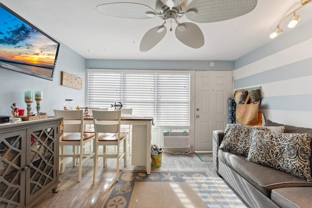 living room featuring ceiling fan, a wall mounted air conditioner, and light wood-type flooring