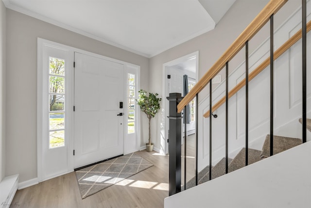 entryway with ornamental molding and light wood-type flooring