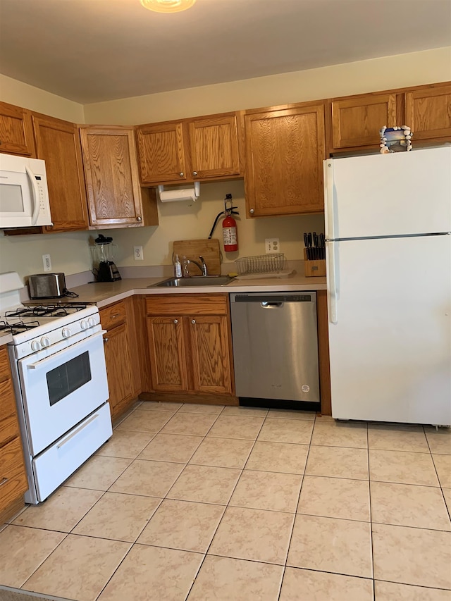 kitchen featuring light tile patterned flooring, white appliances, and sink