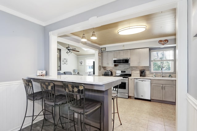 kitchen featuring pendant lighting, a breakfast bar area, stainless steel appliances, a sink, and a peninsula