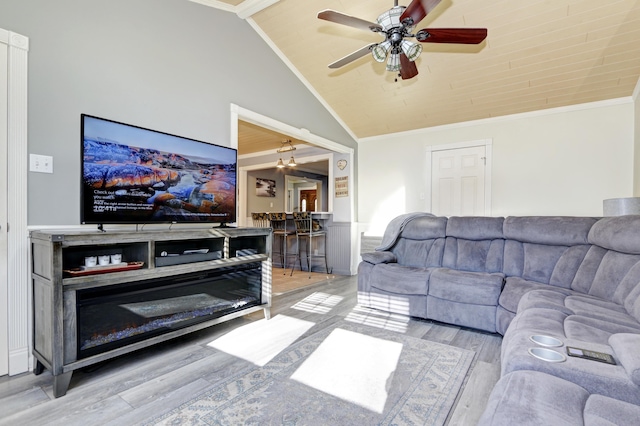 living area with a ceiling fan, lofted ceiling, crown molding, and light wood-style flooring