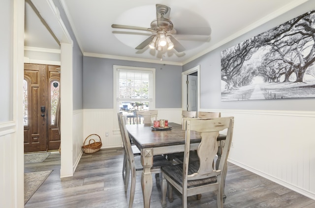 dining area featuring ornamental molding, dark wood-style flooring, wainscoting, and a ceiling fan