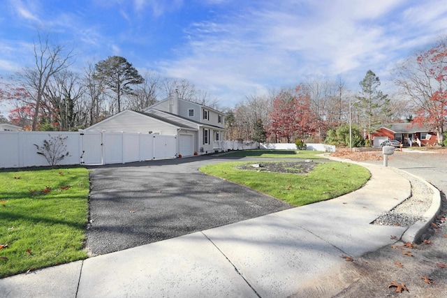 view of property exterior featuring fence, aphalt driveway, and a lawn