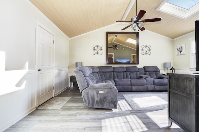 living room featuring a wainscoted wall, ornamental molding, lofted ceiling with skylight, wood finished floors, and wooden ceiling