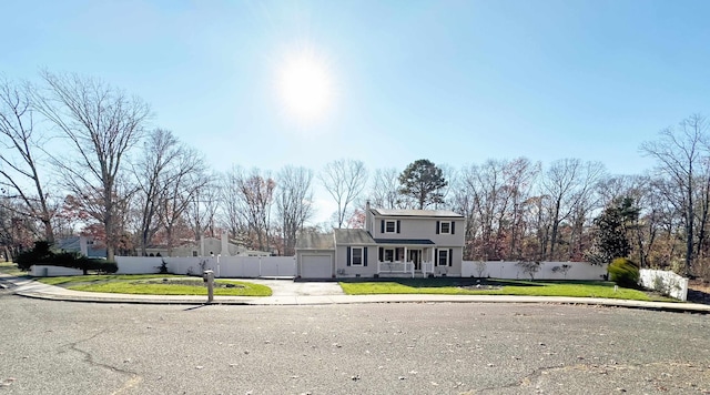 colonial house with driveway, a front lawn, an attached garage, and fence