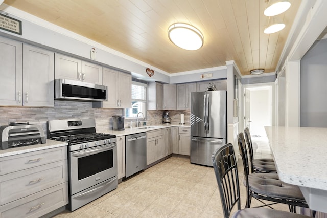 kitchen featuring wooden ceiling, light stone counters, gray cabinets, stainless steel appliances, and backsplash