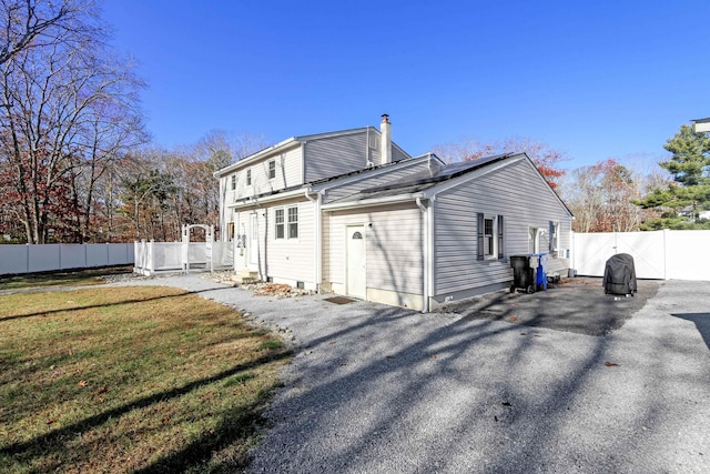 back of property featuring a chimney, a gate, fence, and a yard