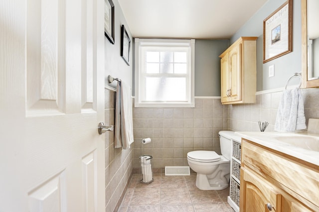 bathroom with toilet, visible vents, tile walls, and vanity