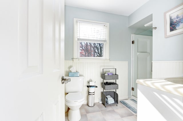 bathroom featuring a wainscoted wall, a shower stall, and toilet