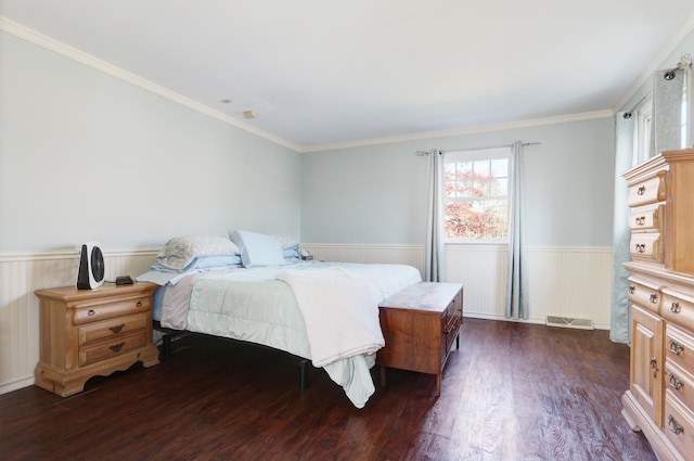 bedroom featuring a wainscoted wall, visible vents, dark wood finished floors, and ornamental molding