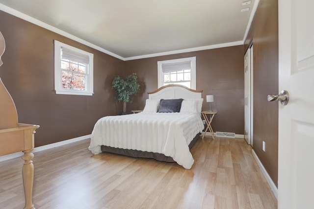 bedroom featuring visible vents, crown molding, light wood-style flooring, and baseboards