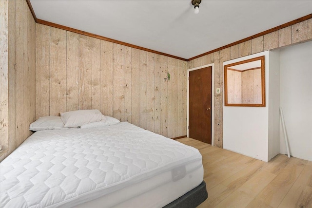 bedroom featuring light hardwood / wood-style floors, ornamental molding, and wooden walls