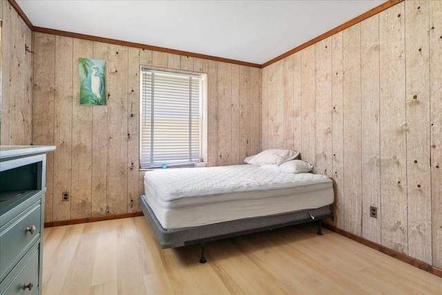 bedroom featuring wooden walls, light hardwood / wood-style flooring, and crown molding