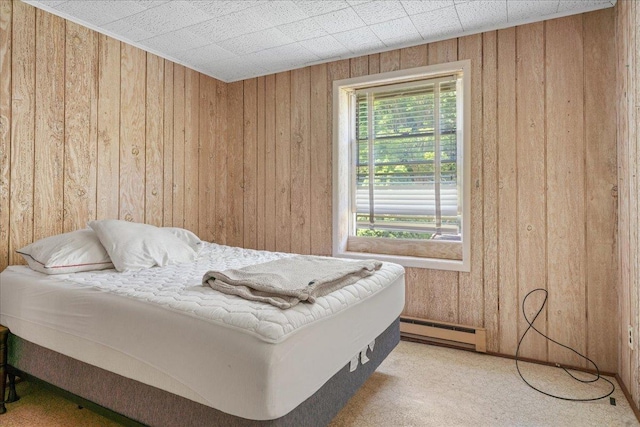 bedroom with carpet flooring, baseboard heating, and wooden walls