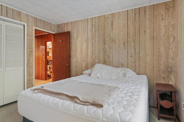 bedroom featuring carpet flooring, wooden walls, and a closet