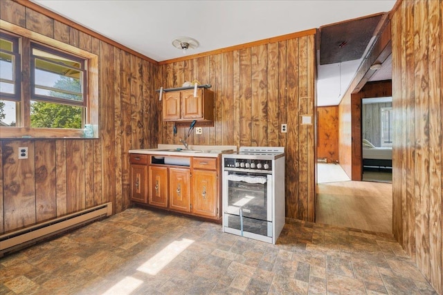 kitchen featuring a baseboard heating unit, wooden walls, white gas stove, and sink