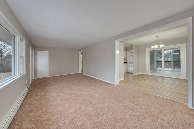 spare room with light carpet, a baseboard heating unit, and a chandelier