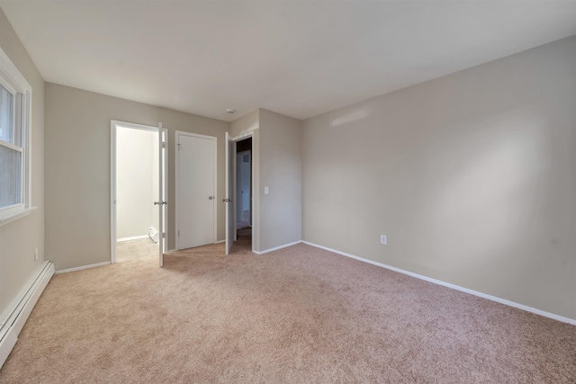 unfurnished bedroom with light carpet and a baseboard heating unit