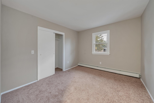 unfurnished bedroom with baseboard heating, a closet, and light carpet