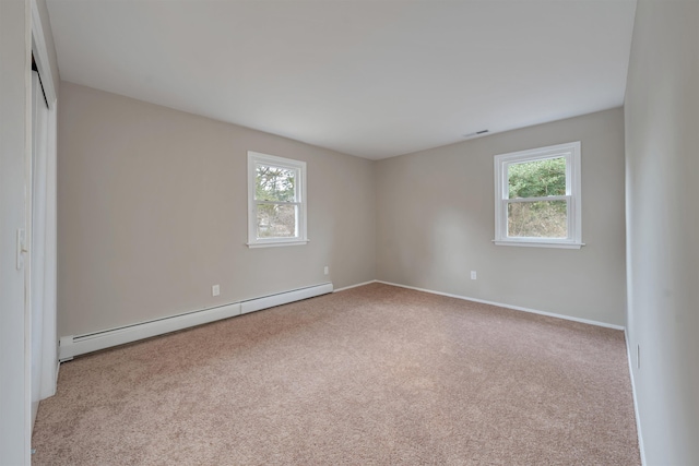 empty room with light carpet, a baseboard radiator, and plenty of natural light