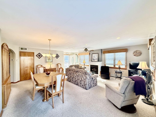 dining room with ceiling fan with notable chandelier, a baseboard heating unit, and light carpet