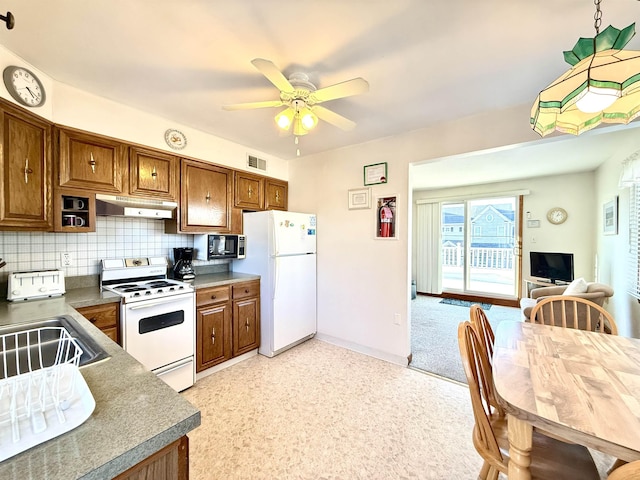 kitchen featuring ceiling fan, sink, backsplash, and white appliances