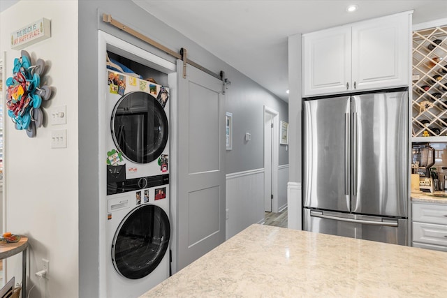 clothes washing area with a barn door, stacked washer and dryer, and wood-type flooring