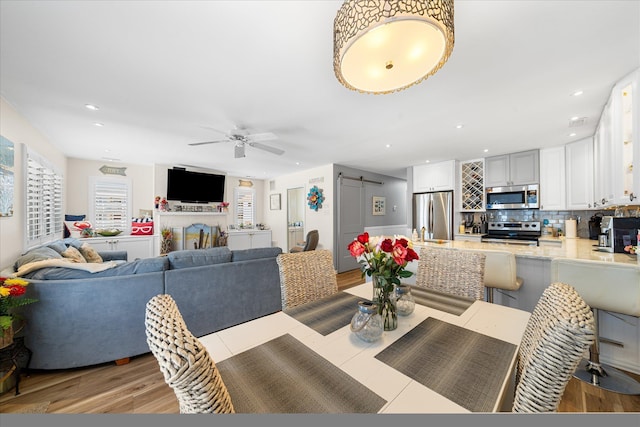 dining area featuring ceiling fan and a barn door