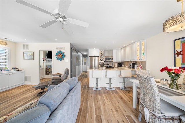 living room with light wood-type flooring and ceiling fan