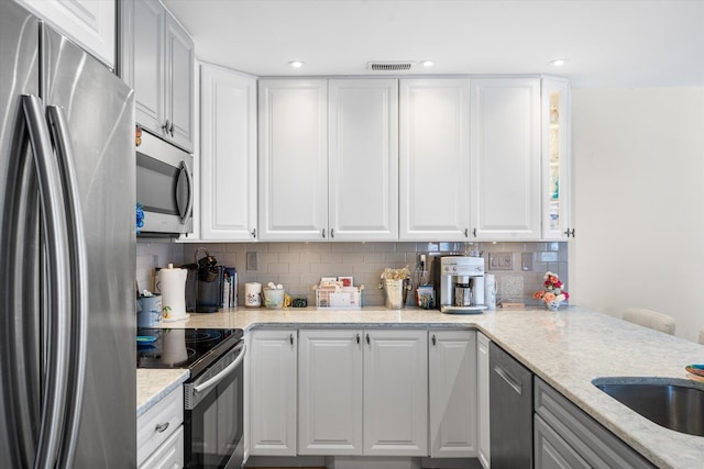 kitchen featuring light stone countertops, white cabinetry, appliances with stainless steel finishes, and tasteful backsplash