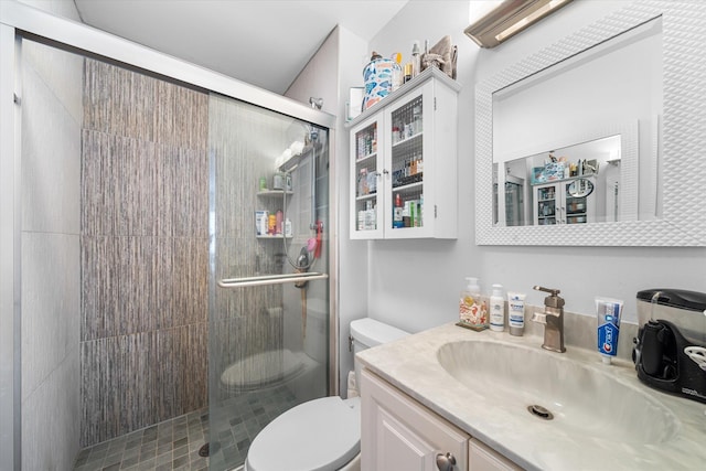 bathroom with vanity, a shower with shower door, and toilet