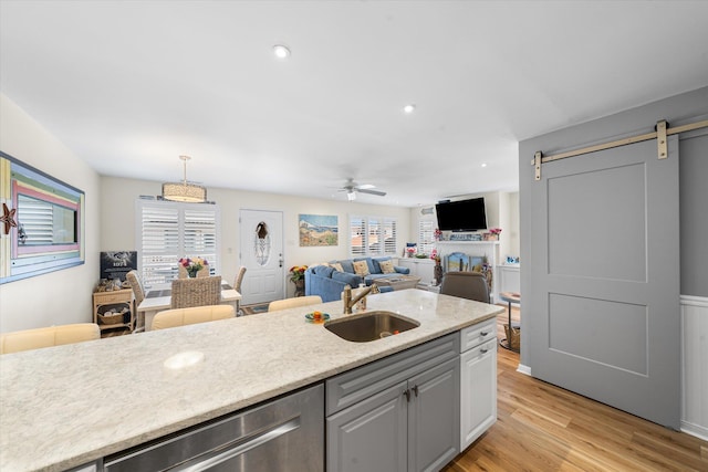 kitchen with dishwasher, sink, ceiling fan, a barn door, and decorative light fixtures