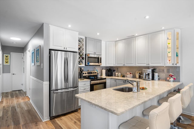 kitchen featuring a breakfast bar, sink, white cabinetry, kitchen peninsula, and stainless steel appliances