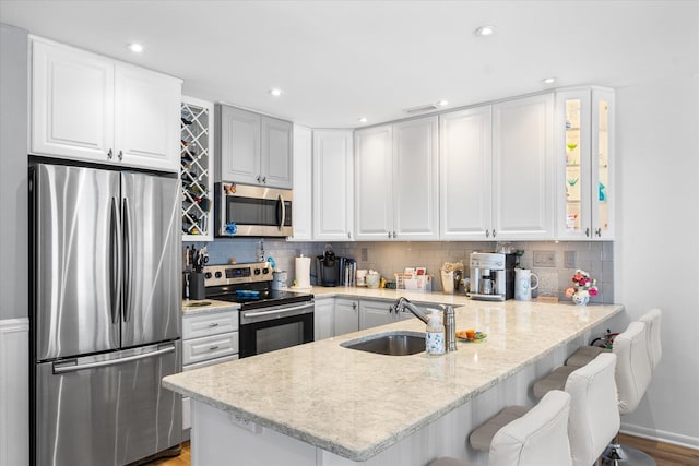 kitchen with a breakfast bar area, white cabinetry, sink, and appliances with stainless steel finishes