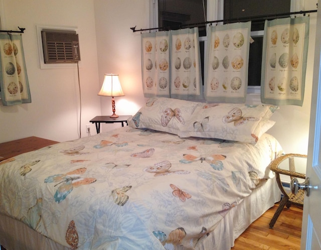 bedroom featuring a wall mounted AC and light hardwood / wood-style flooring