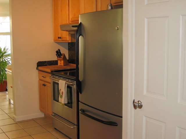 kitchen featuring stainless steel fridge, stove, and light tile patterned flooring