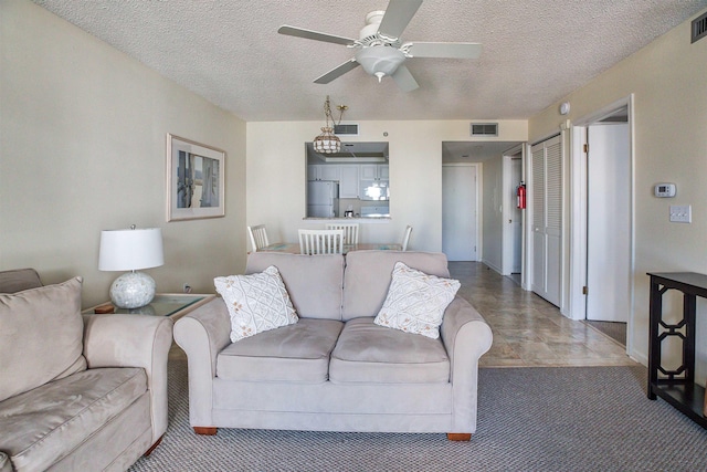 living room with ceiling fan and a textured ceiling