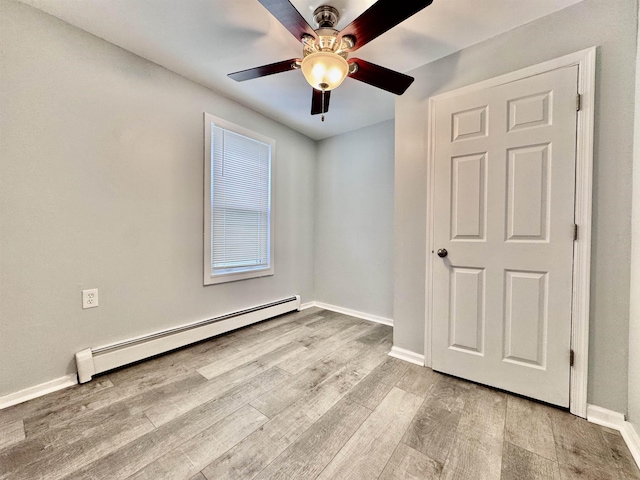 spare room featuring ceiling fan, baseboard heating, and light hardwood / wood-style flooring