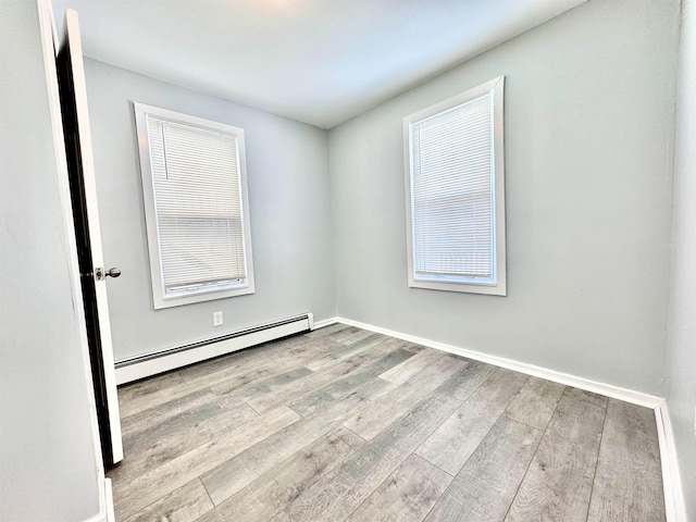 empty room with baseboard heating and light hardwood / wood-style flooring