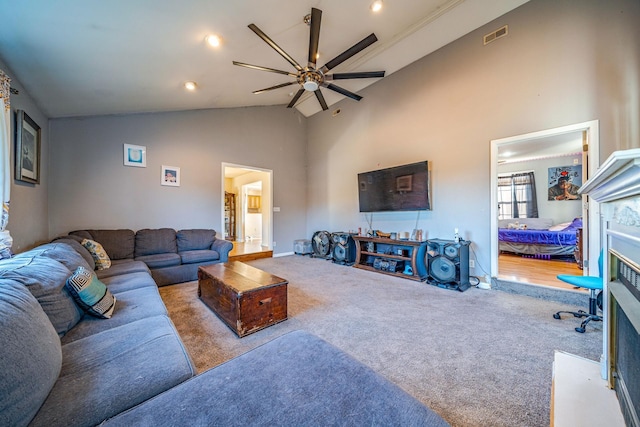 carpeted living room with ceiling fan, a premium fireplace, and high vaulted ceiling