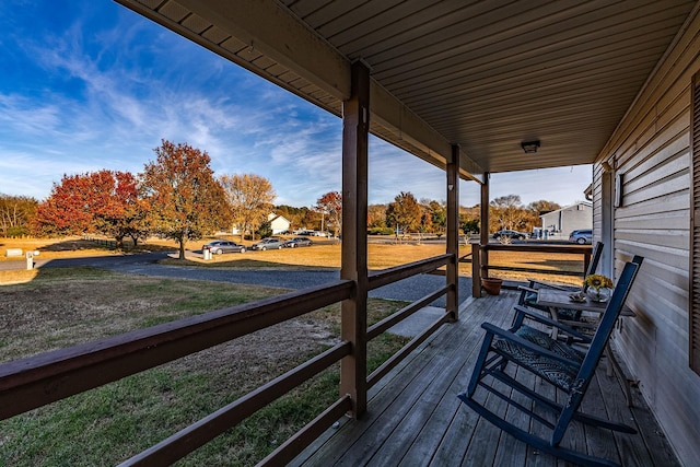 wooden terrace featuring a porch and a yard