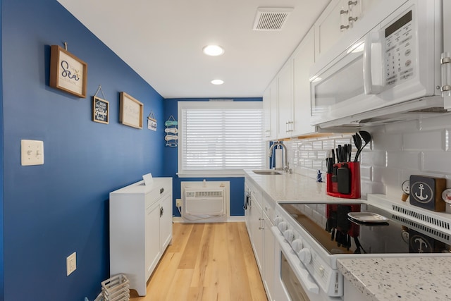 kitchen featuring backsplash, stove, white cabinets, and a wall mounted air conditioner