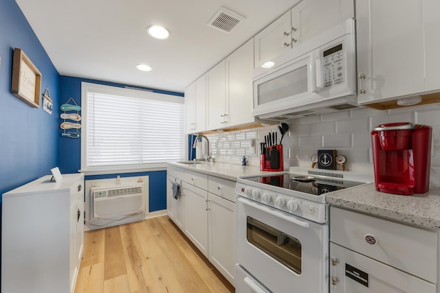 kitchen with white appliances, white cabinets, sink, decorative backsplash, and light wood-type flooring