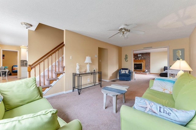 living room with a brick fireplace, light carpet, a textured ceiling, and ceiling fan