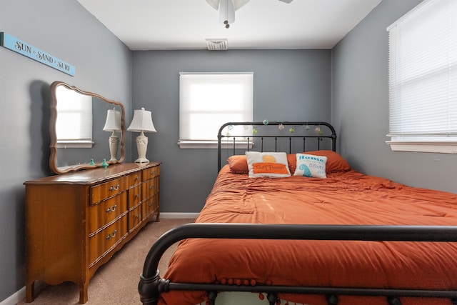 bedroom featuring ceiling fan, multiple windows, and light carpet