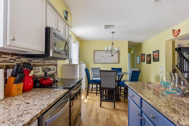 25 N 12th St, Del Haven, NJ 08251 - kitchen featuring appliances with stainless steel finishes, blue cabinets, a chandelier, backsplash, and light wood-style floors