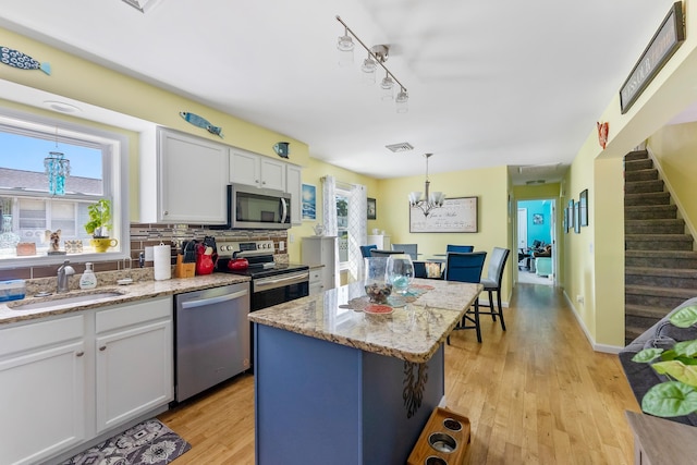 25 N 12th St, Del Haven, NJ 08251 - kitchen featuring appliances with stainless steel finishes, a sink, white cabinets, light wood-type flooring, and hanging light fixtures