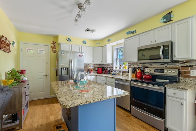 25 N 12th St, Del Haven, NJ 08251 - kitchen with stainless steel appliances, white cabinetry, backsplash, light wood finished floors, and a center island