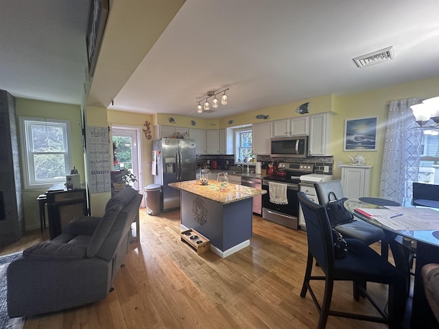 25 N 12th St, Del Haven, NJ 08251 - kitchen with appliances with stainless steel finishes, white cabinetry, a kitchen island, tasteful backsplash, and light wood-type flooring
