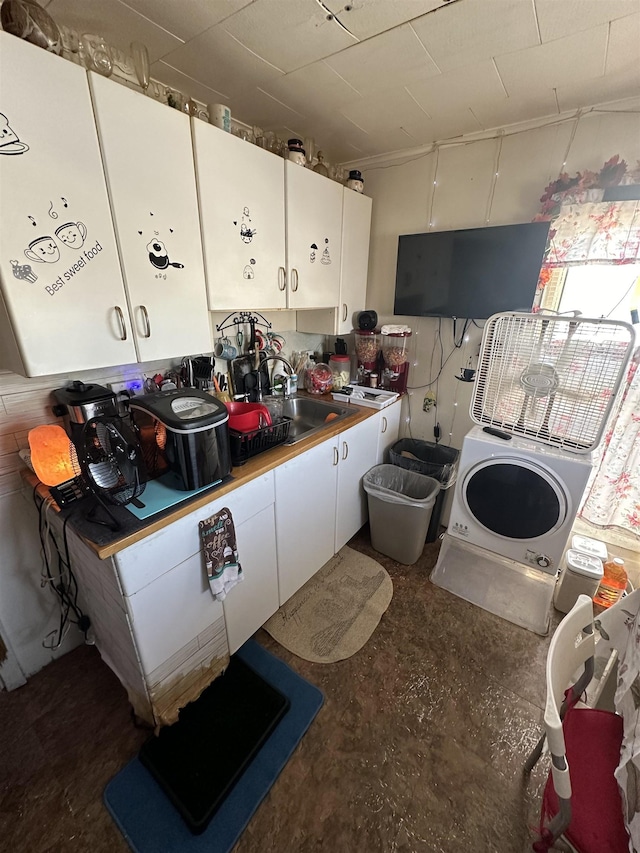 interior space featuring white cabinetry, sink, and washer / dryer